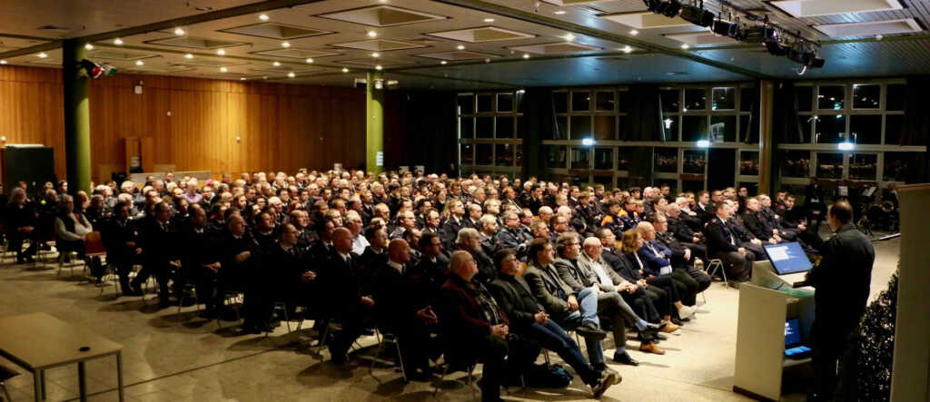 Ein Saal mit hunderten Feuerwehrleuten die einem Vortrag folgen
