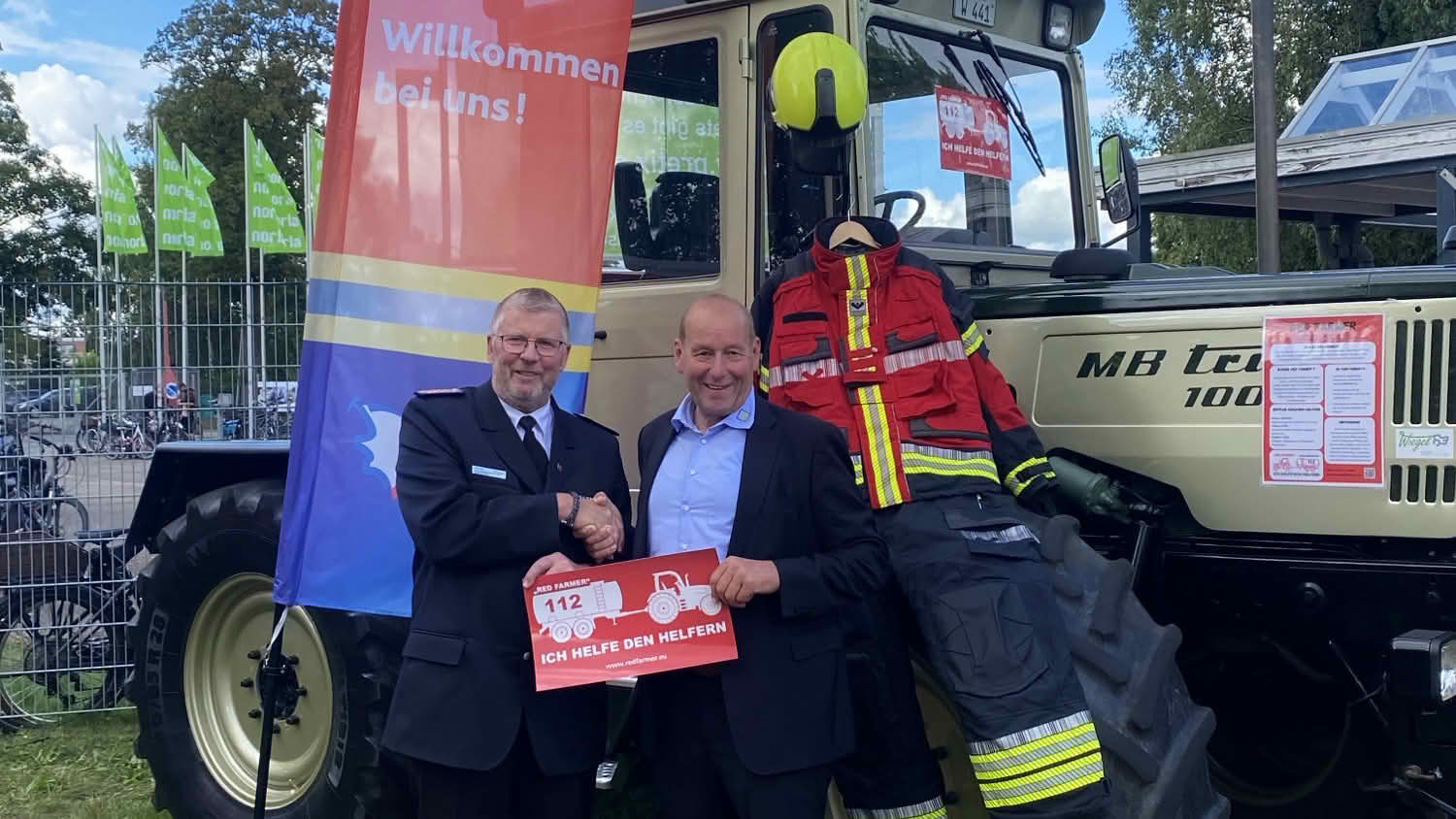 Landesbrandmeister Jörg Nero und Klaus-Peter Lucht besiegeln die Zusammenarbeit bei "Red Farmer" Initiative vor einen Traktor