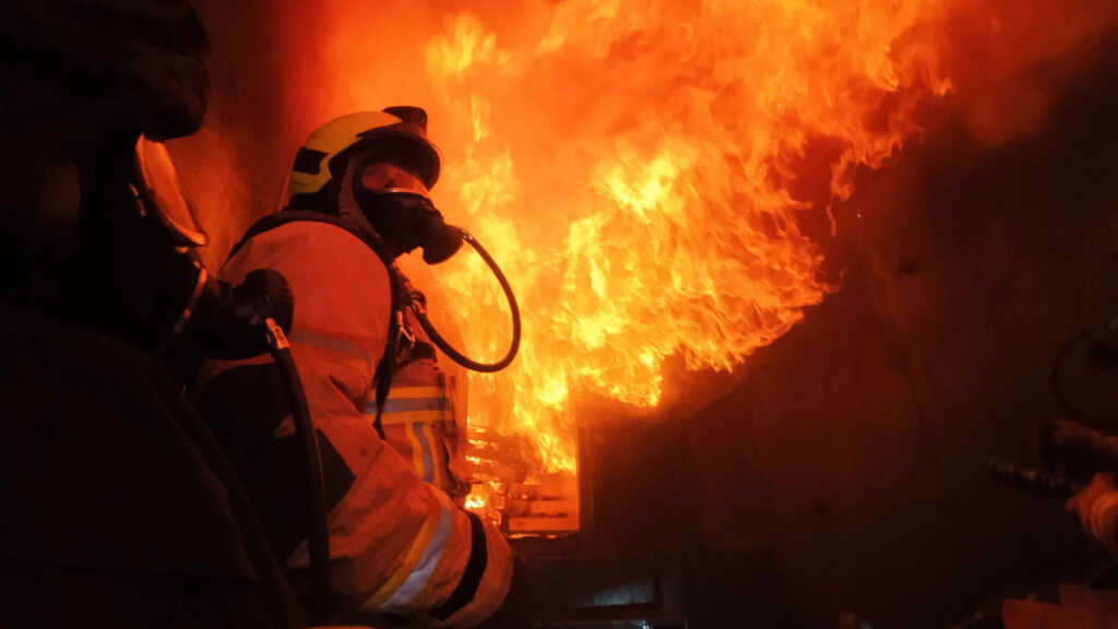 Feuerwehrmann unter Flammen im Übungscontainer