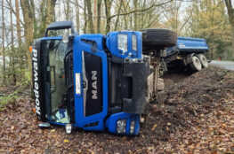 LKW kommt von Straße ab und kippt um